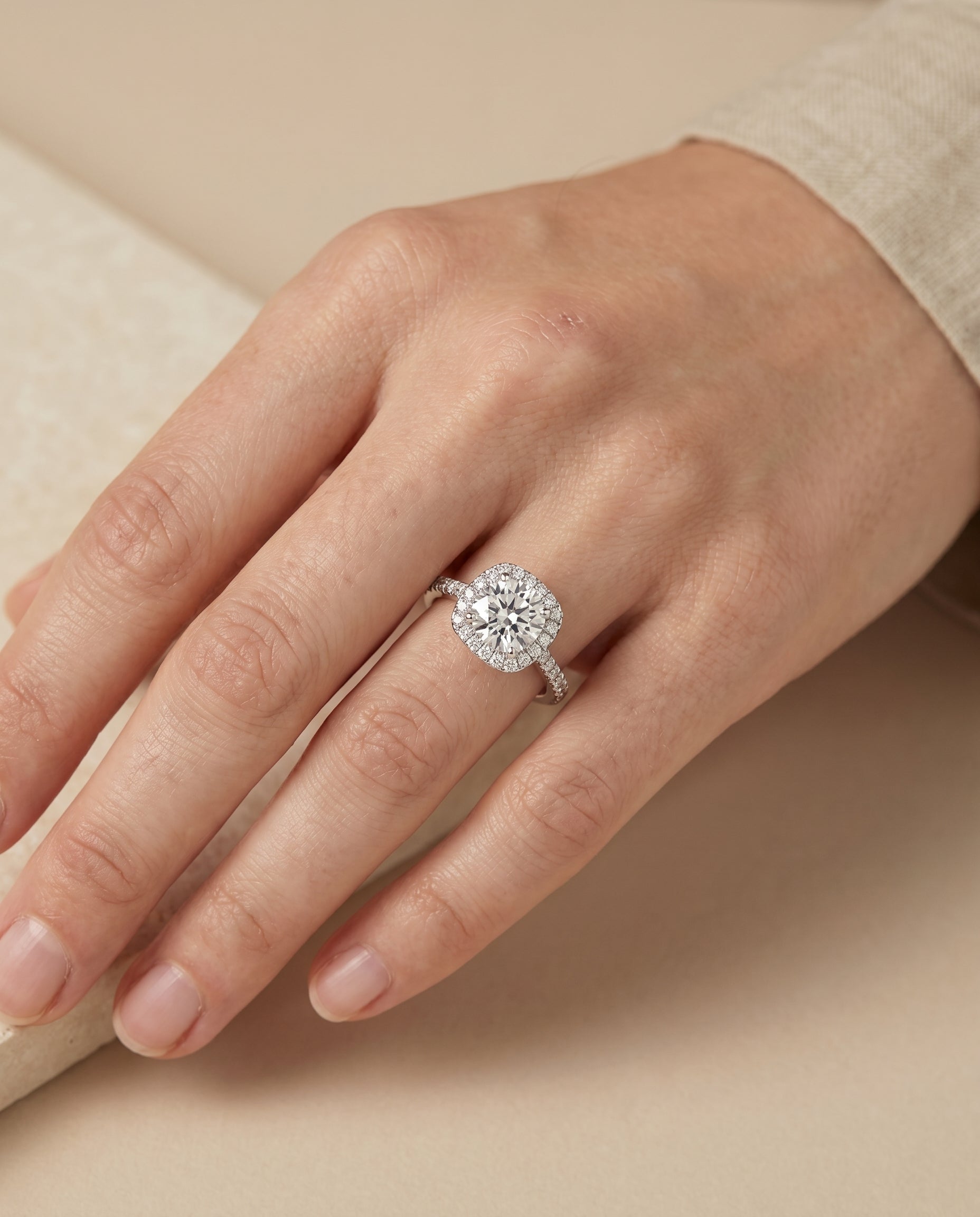Everly Select Classic Shared Prong Halo Round Lab Diamond Engagement Ring in Platinum, shown on hand, angled | RockHer