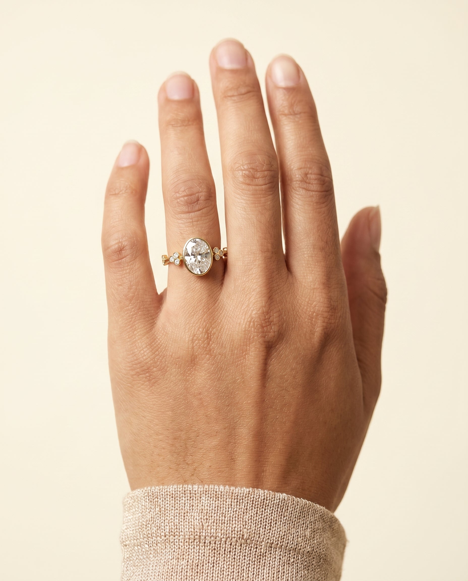 Miley Select Clover Bezel Accent Solitaire Oval Lab Diamond Engagement Ring in 18K Yellow Gold, shown on hand | RockHer