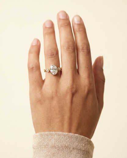 Miley Select Clover Bezel Accent Solitaire Oval Lab Diamond Engagement Ring in 18K Yellow Gold, shown on hand | RockHer