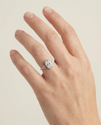 Selena Select Clover Bezel Accent Solitaire Oval Lab Diamond Engagement Ring in Platinum, shown on hand | RockHer