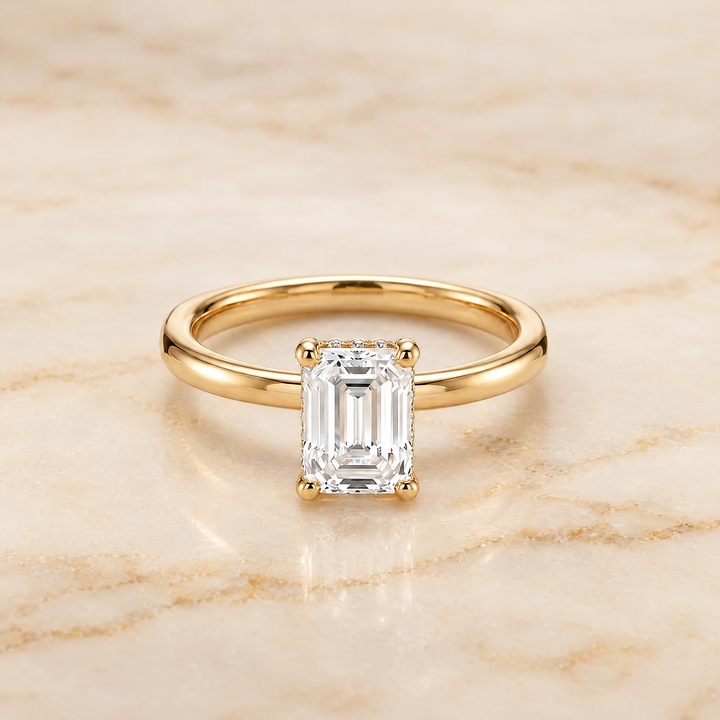 The Lana Secret Halo Adorned Prong Solitaire Emerald Cut Engagement Ring Setting in 18K Yellow Gold