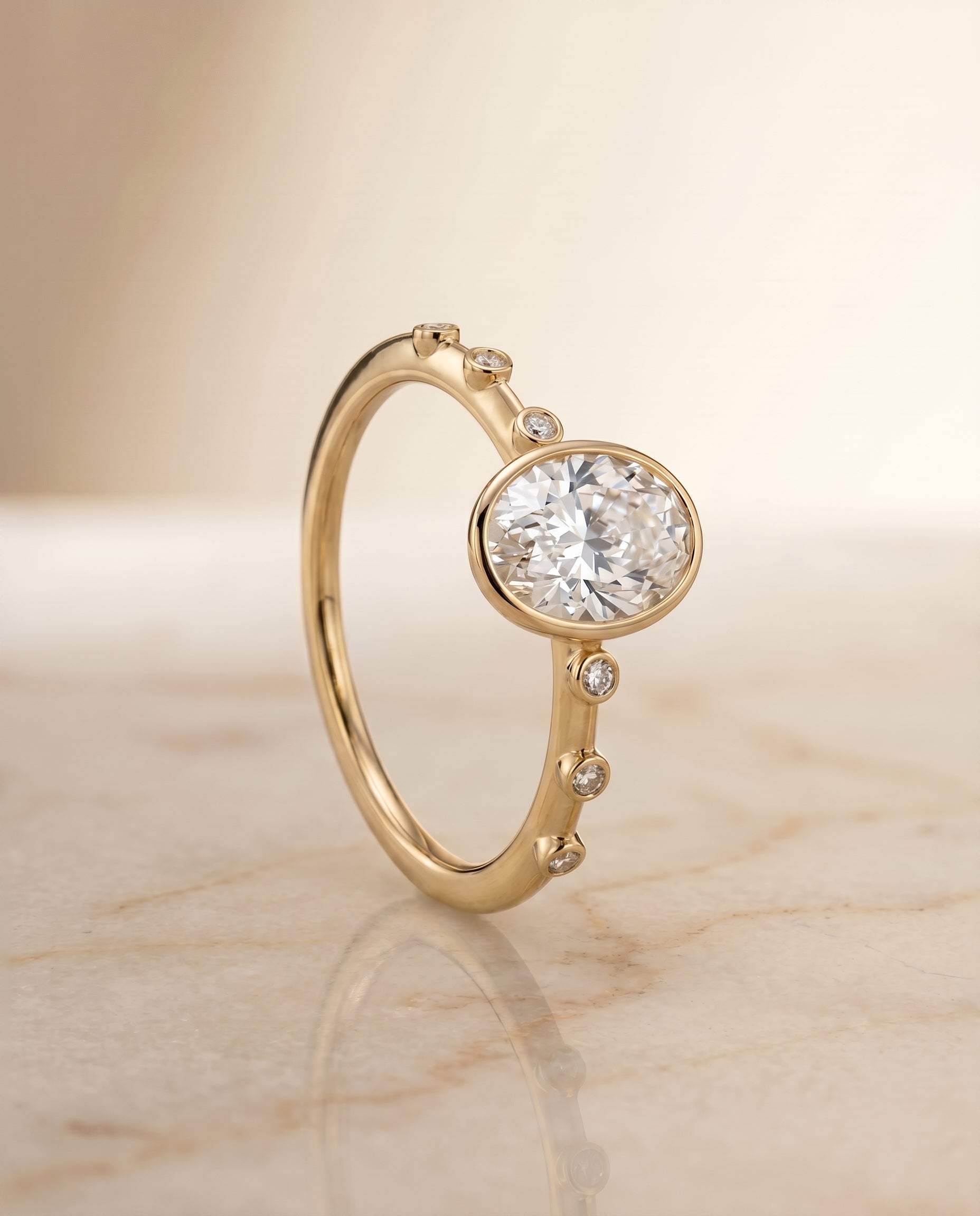 The Brandi bezel accent solitaire engagement ring setting for oval diamonds in 18k yellow gold engagement ring setting, sh...