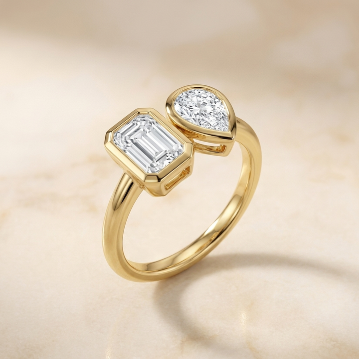 18K Yellow Gold Josephine Select Toi et Moi Emerald & Pear Bezel Set Lab Diamond Engagement Ring - Alt angle on warm marble