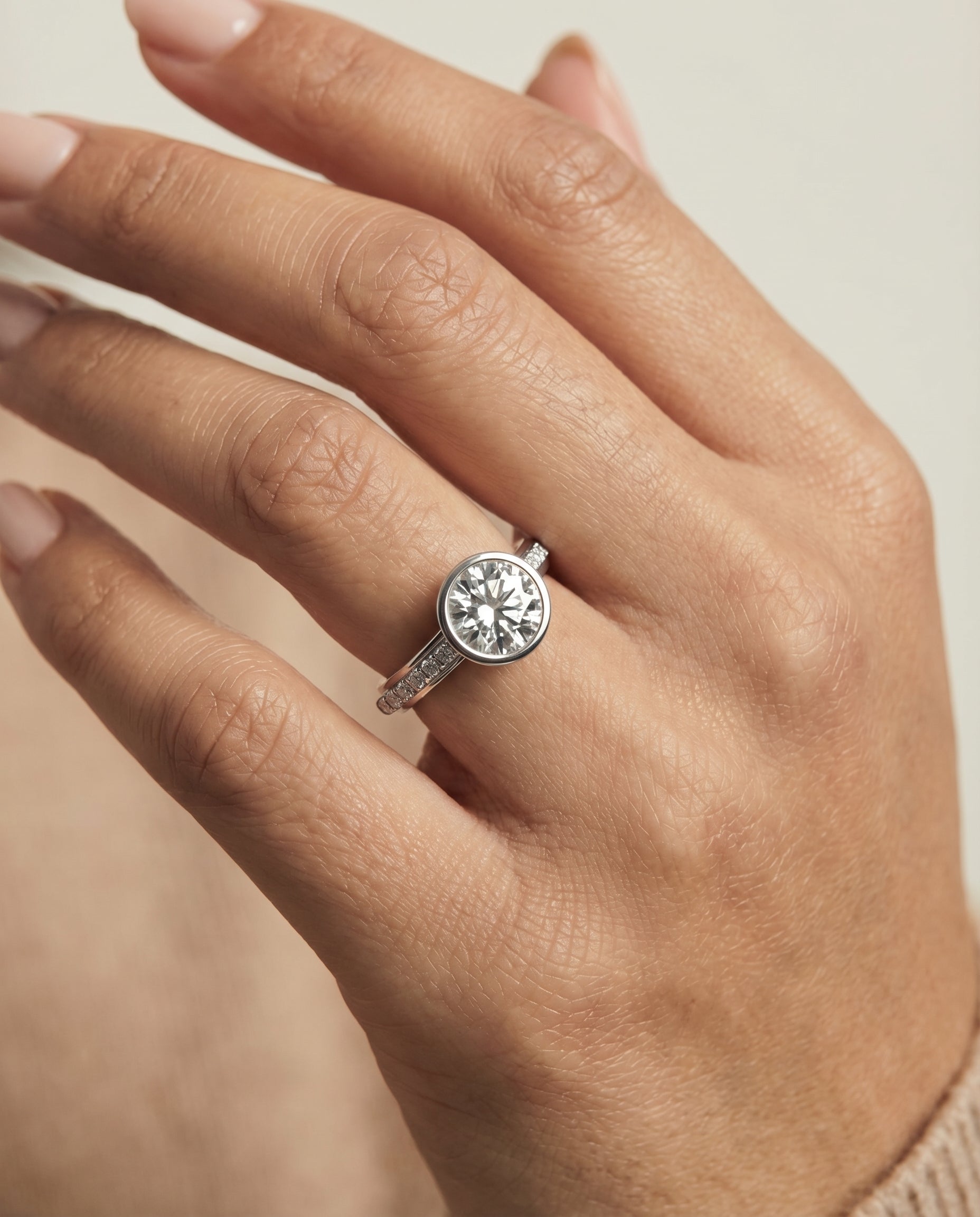 Cappella Select Bezel Solitaire Round Lab Diamond Engagement Ring in Platinum, shown on hand, angled | RockHer