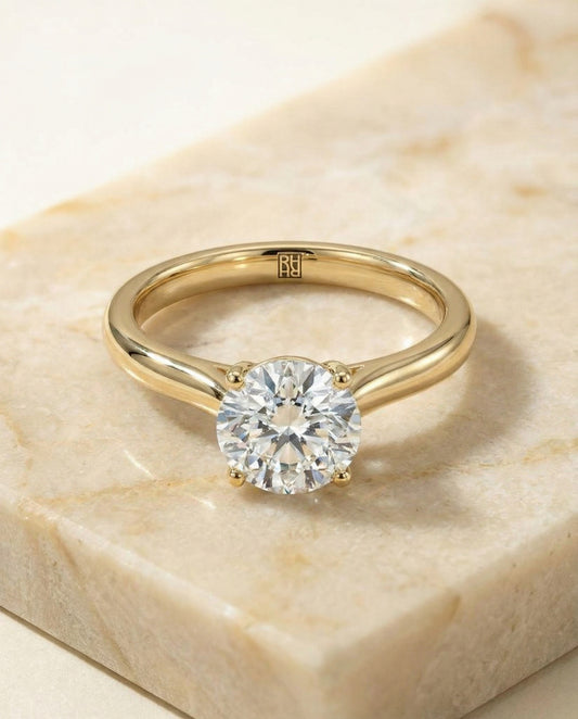 Round Brilliant, Pinched Cathedral Solitaire, in 18K Yellow Gold, prong setting – angled view | RockHer