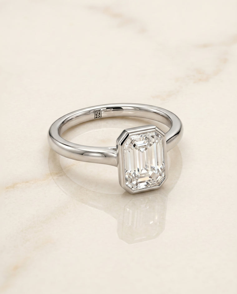 The Duran Simple Bezel Solitaire Emerald Cut Engagement Ring Setting in 18K White Gold