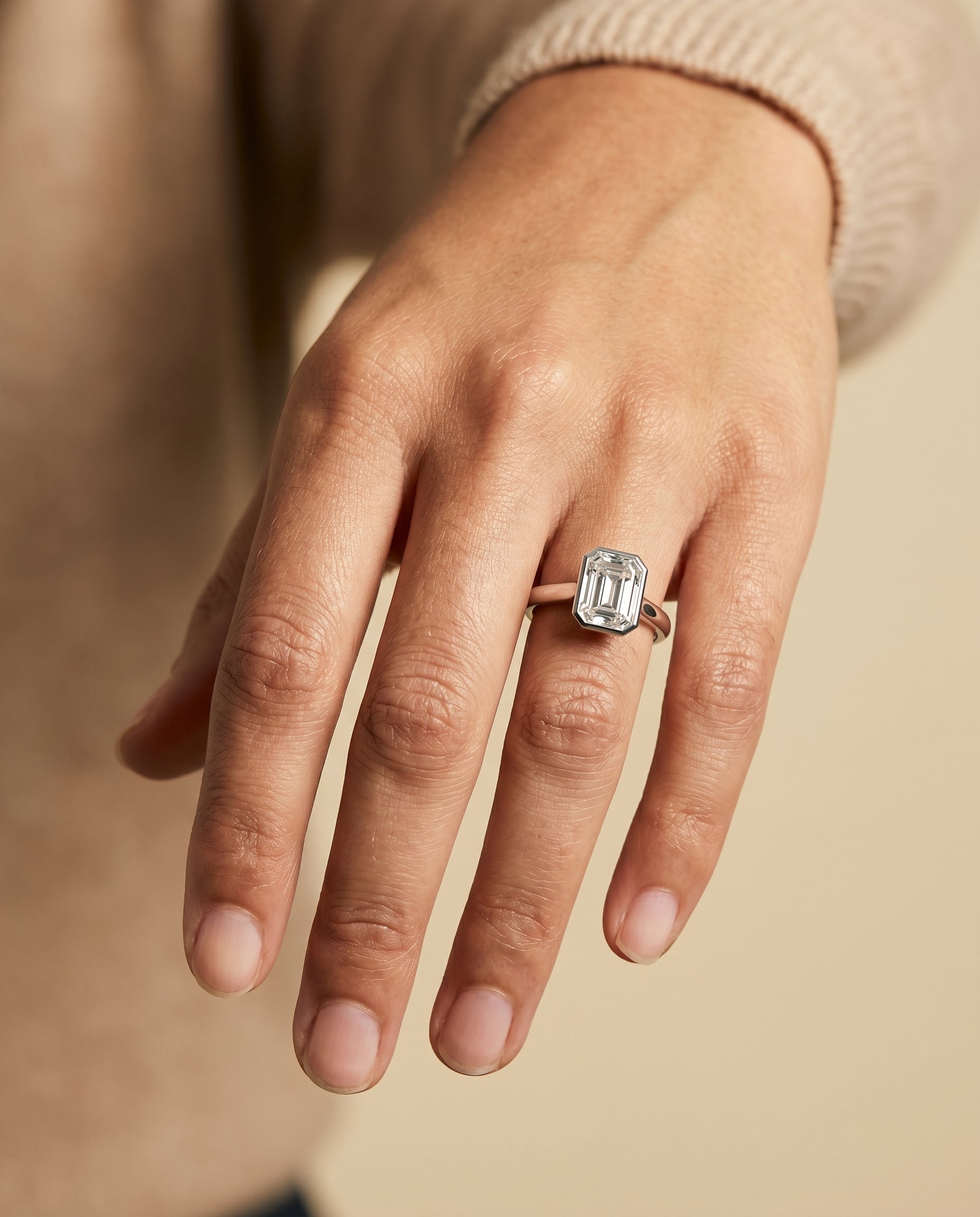 Duran Select Simple Bezel Solitaire Emerald Cut Lab Diamond Engagement Ring in Platinum, shown on hand | RockHer