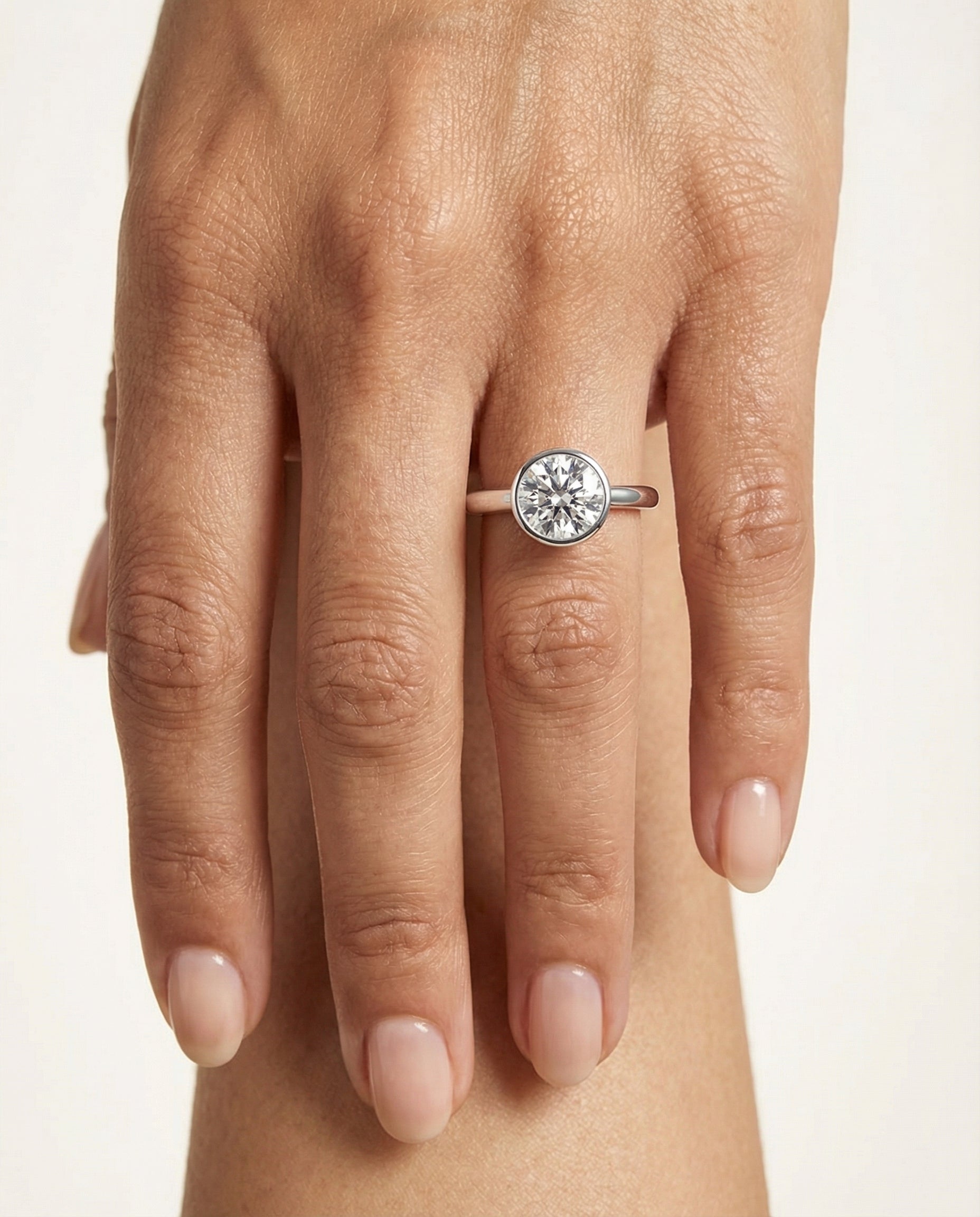 Duran Select Simple Bezel Solitaire Round Lab Diamond Engagement Ring in Platinum, shown on hand | RockHer