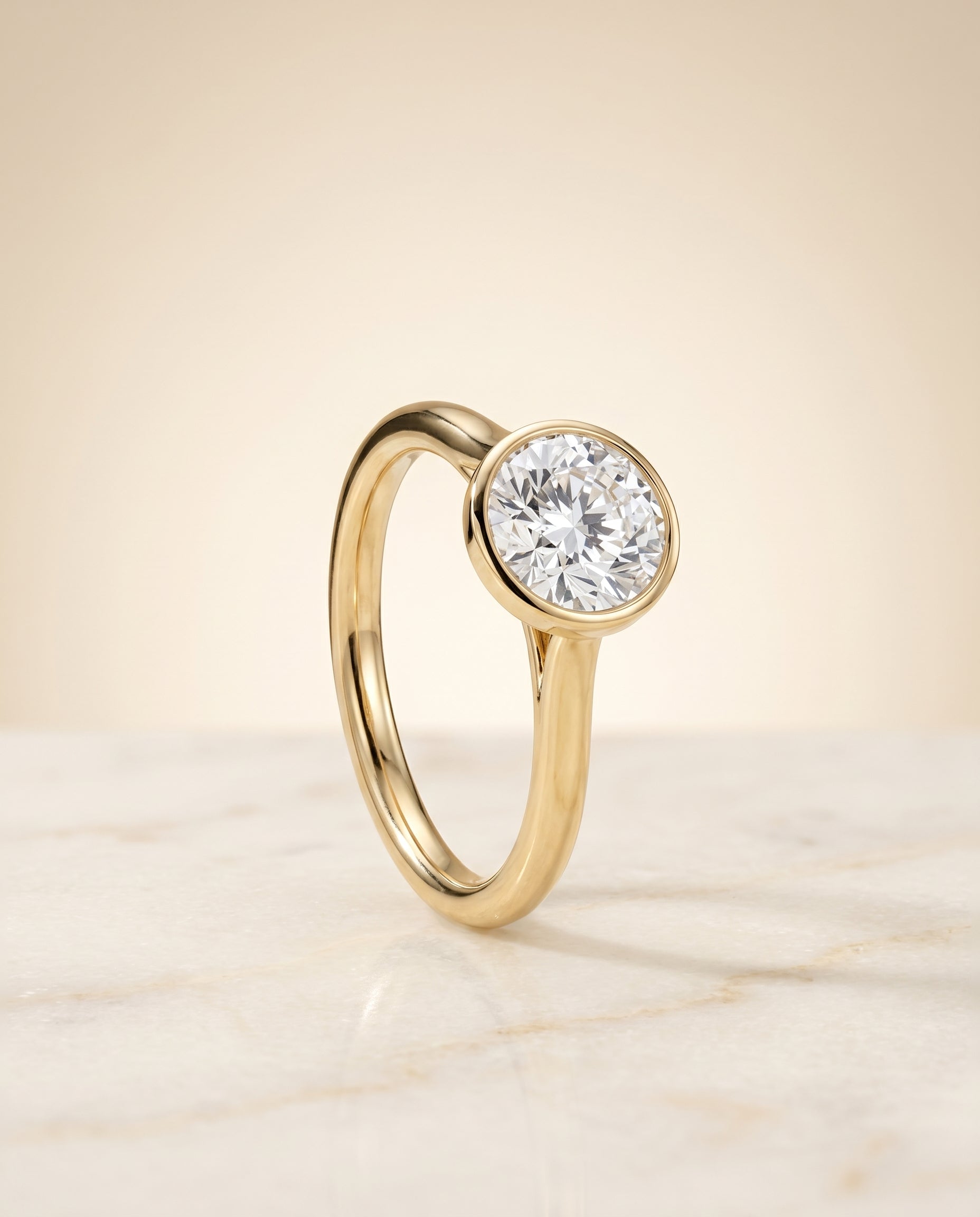 Duran Select Simple Bezel Solitaire Round Lab Diamond Engagement Ring in 18K Yellow Gold, shown on hand, angled | RockHer