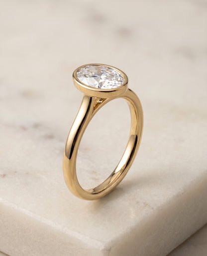 The Duran Simple Bezel Solitaire Oval Engagement Ring Setting in 18K Yellow Gold