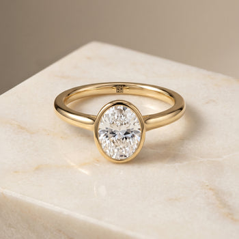 The Duran Simple Bezel Solitaire Oval Engagement Ring Setting in 18K Yellow Gold