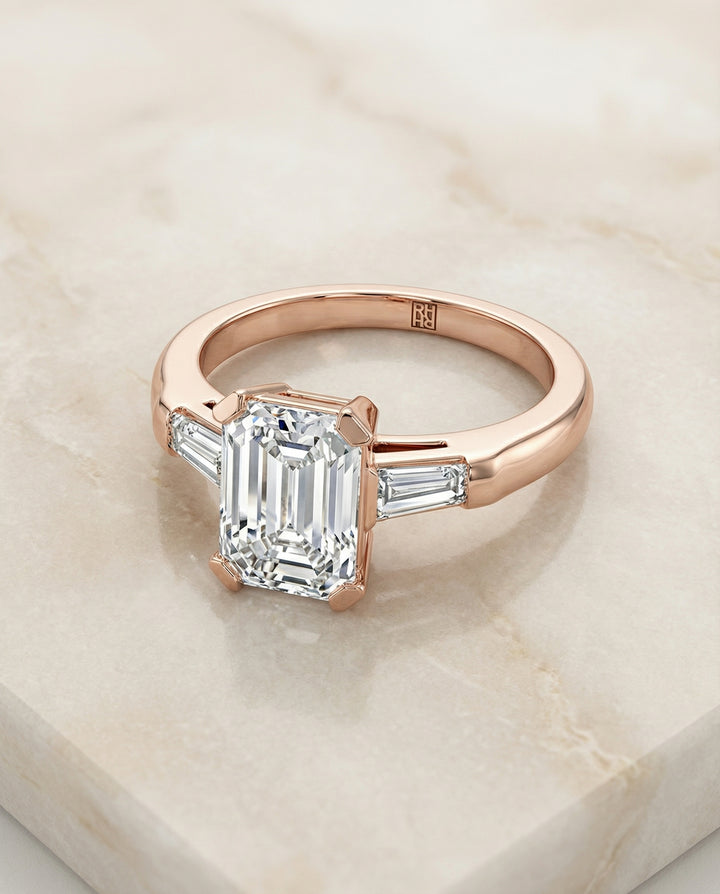 European Cut, Tapered Baguette Three Stone Emerald, in 14K Rose Gold, prong setting – angled view | RockHer