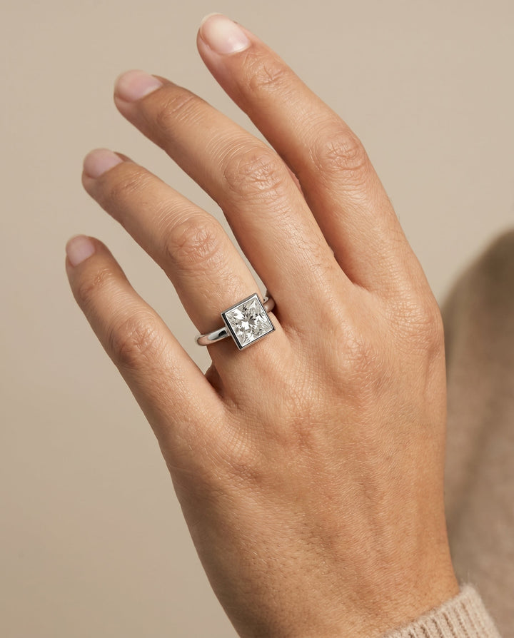 Agnes Select Bezel Solitaire In Princess Cut Lab Diamond Engagement Ring in Platinum, shown on hand | RockHer