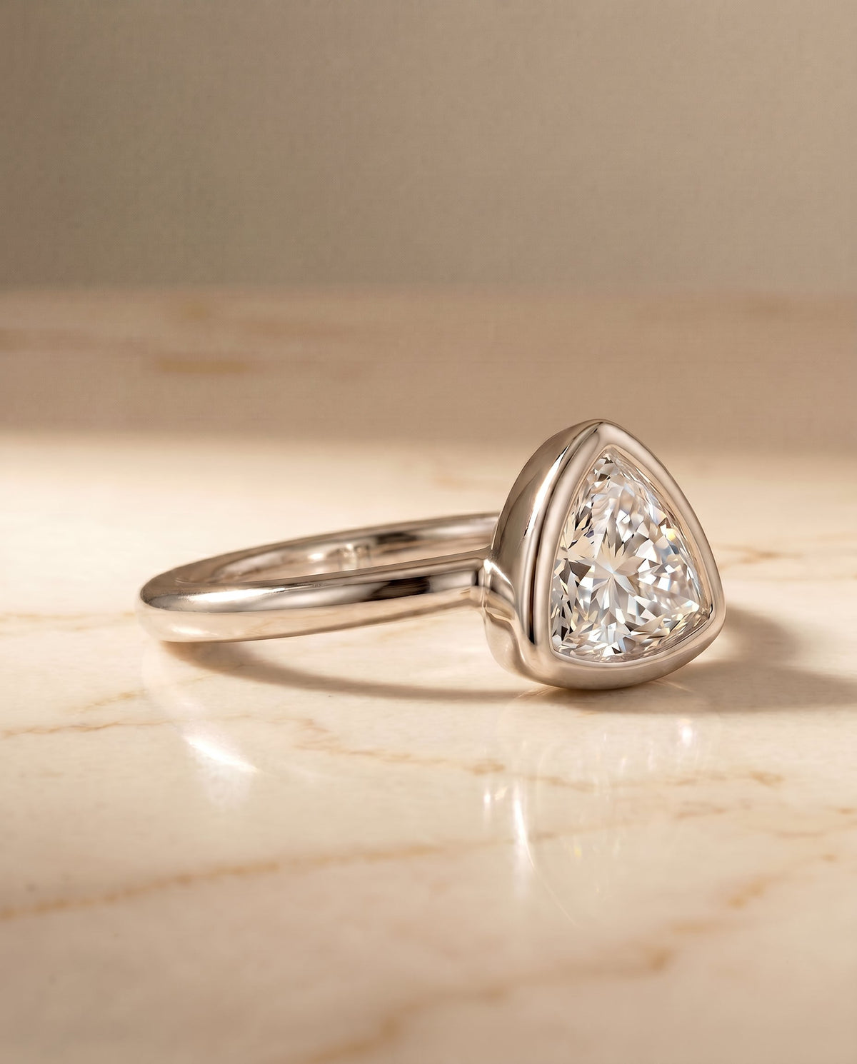 Agnes Select Bezel Solitaire Trillion Lab Diamond Engagement Ring in Platinum, shown on hand, angled | RockHer