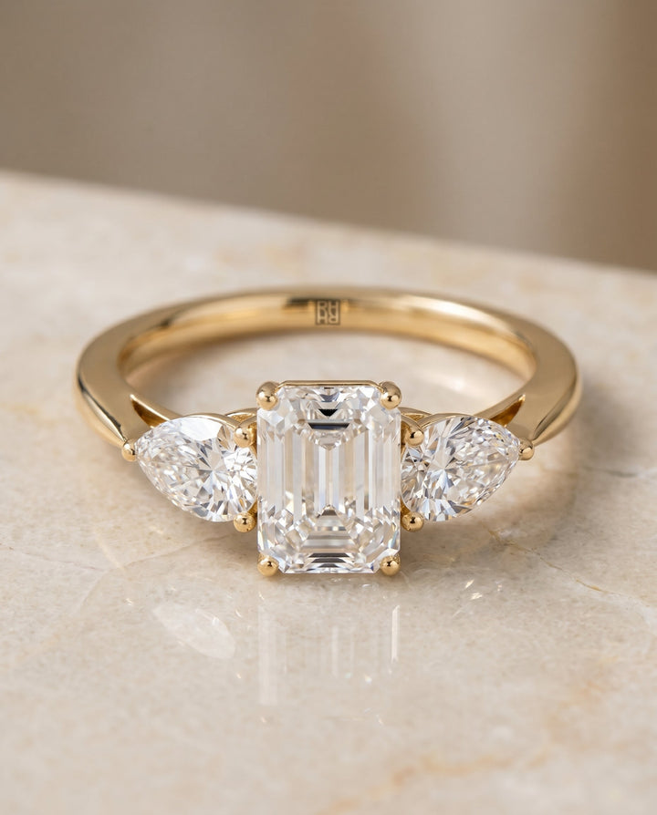 Angelica Select Three Stone Emerald Cut Lab Diamond Engagement Ring in 18K Yellow Gold, shown on hand, angled | RockHer