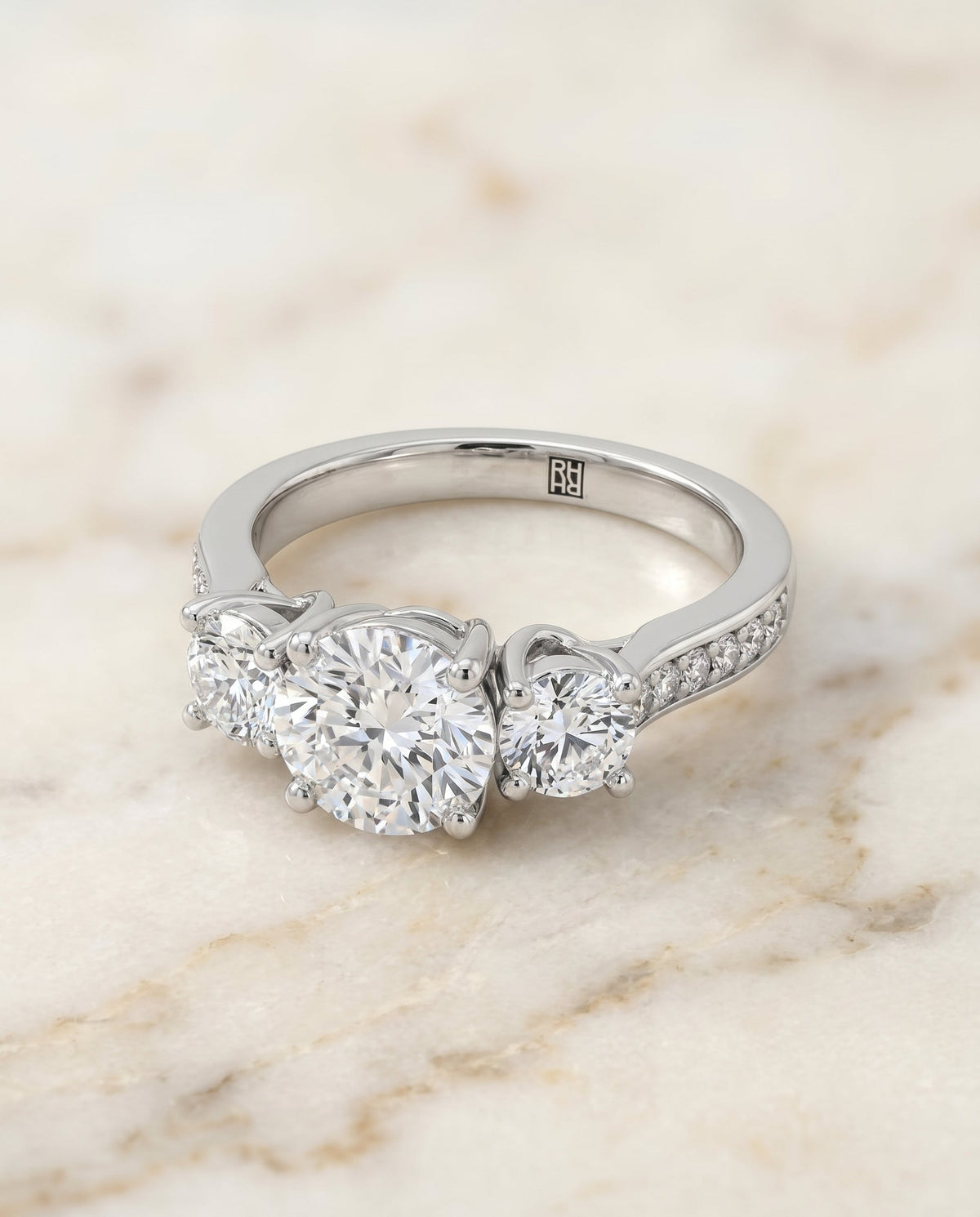 Avery Select Three Stone Round Lab Diamond Engagement Ring in Platinum, shown on hand, angled | RockHer