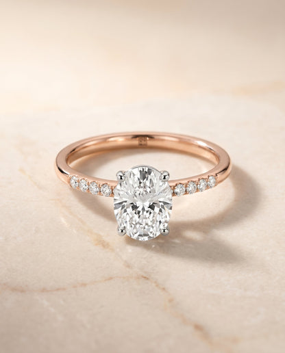 Cherie Select Hidden Halo Pavé Solitaire Oval Lab Diamond Engagement Ring in 14K Rose Gold, shown on hand, angled | RockHer