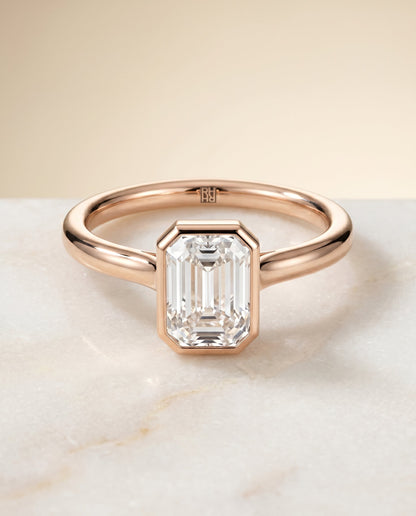 Duran Select Simple Bezel Solitaire Emerald Cut Lab Diamond Engagement Ring in 14K Rose Gold, shown on hand, angled | RockHer