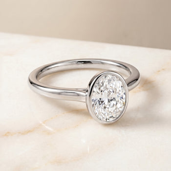 The Duran Simple Bezel Solitaire Oval Engagement Ring Setting in 18K White Gold