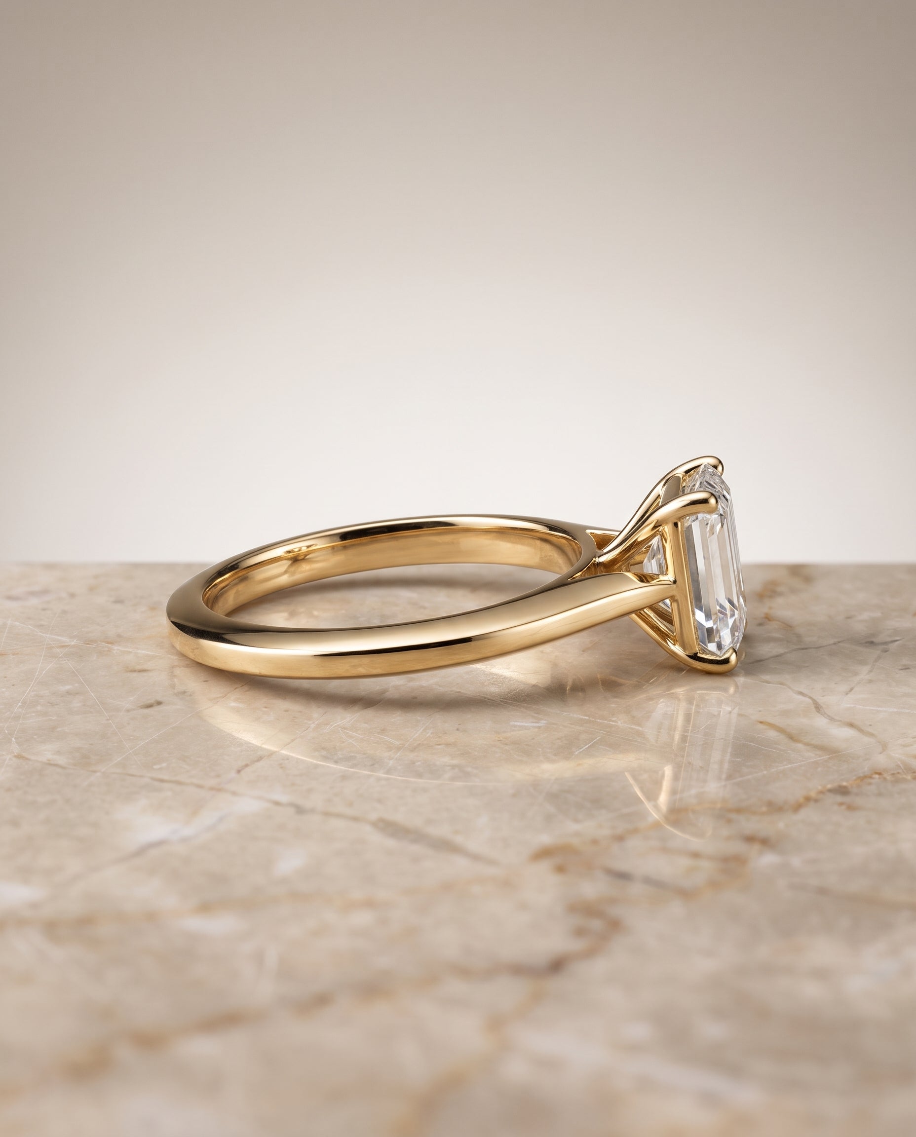 The Elena Timeless Graduated Beveled Shank Solitaire Emerald Cut Engagement Ring Setting in 18K Yellow Gold