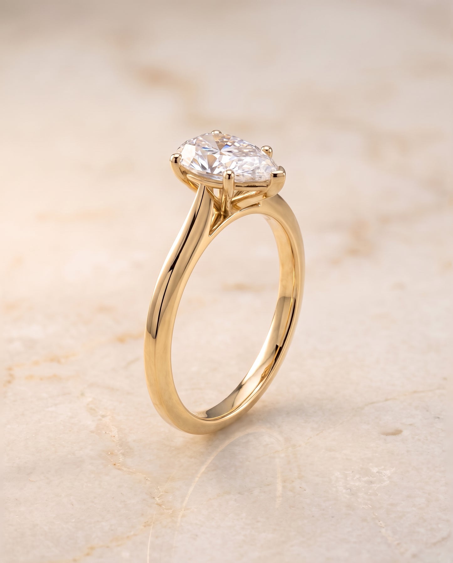 The Elena Timeless Graduated Beveled Shank Solitaire Pear Engagement Ring Setting in 18K Yellow Gold
