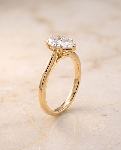 The Elena Timeless Graduated Beveled Shank Solitaire Pear Engagement Ring Setting in 18K Yellow Gold