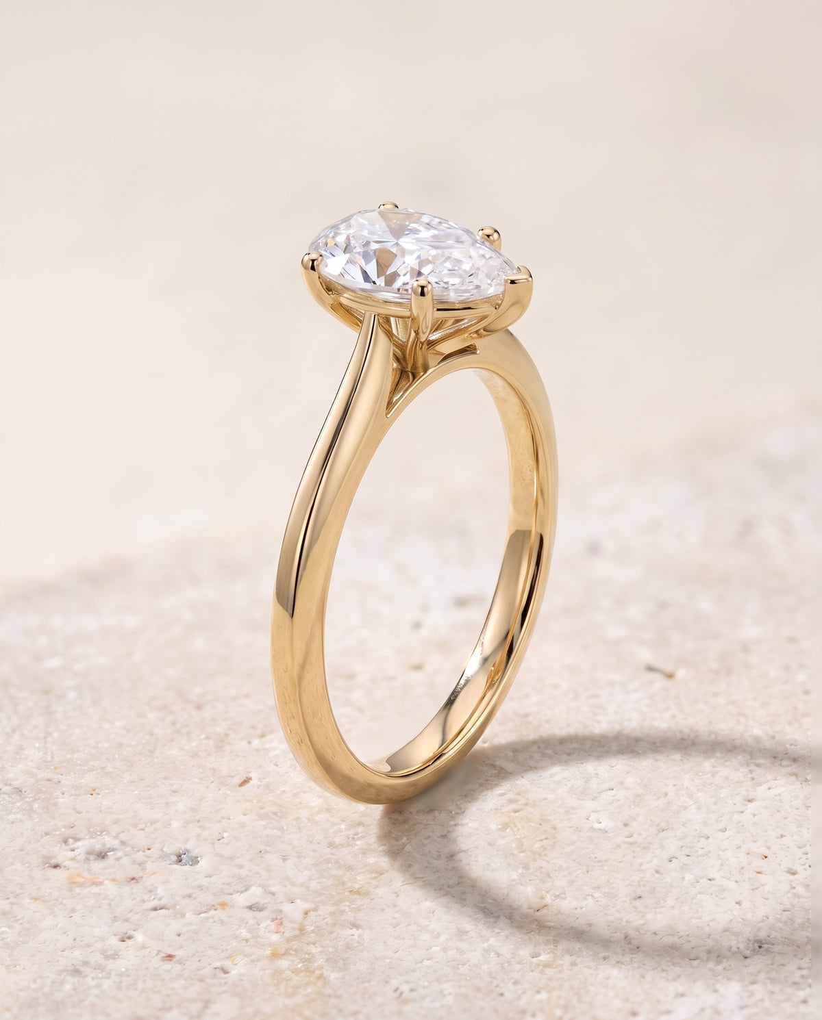 The Elena Timeless Graduated Beveled Shank Solitaire Pear Engagement Ring Setting in 18K Yellow Gold