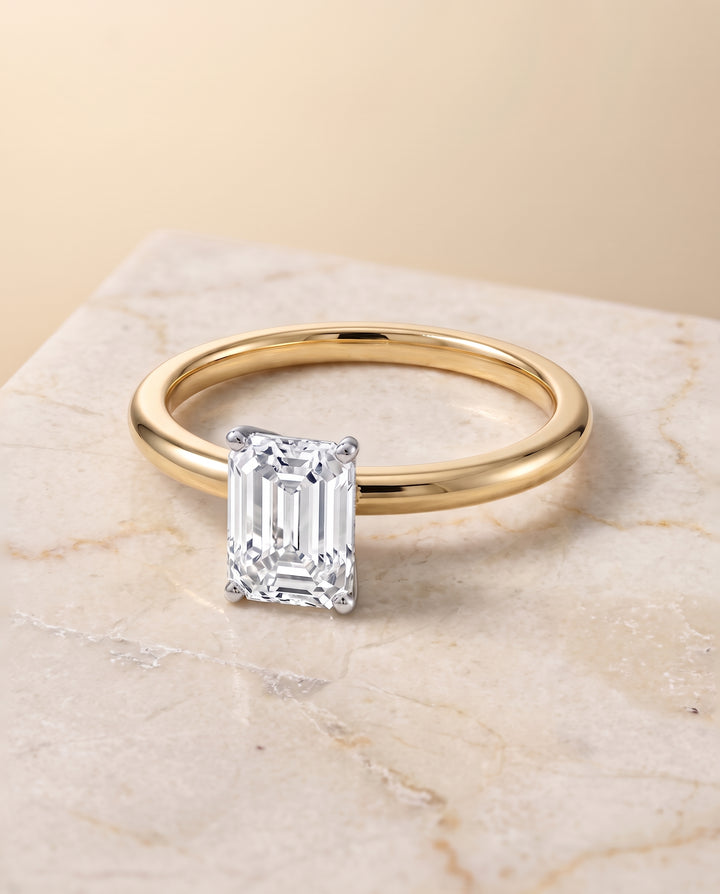 The Floria Comfort Fit Claw Prong Solitaire Emerald Cut Engagement Ring Setting in 18K Yellow Gold