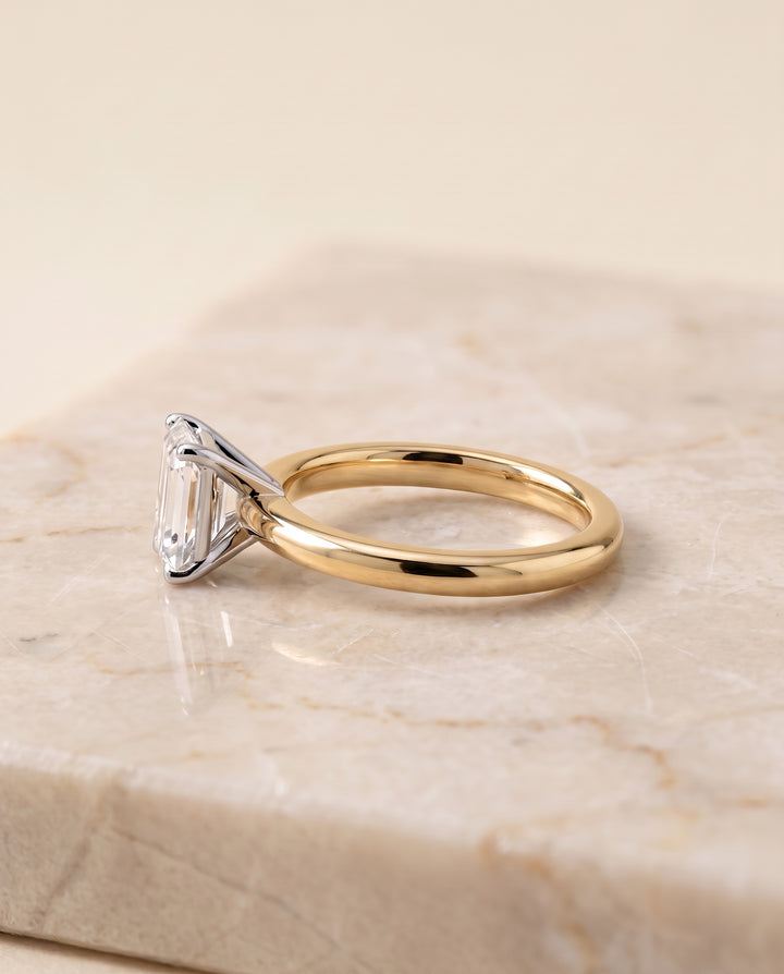 The Floria Comfort Fit Claw Prong Solitaire Emerald Cut Engagement Ring Setting in 18K Yellow Gold