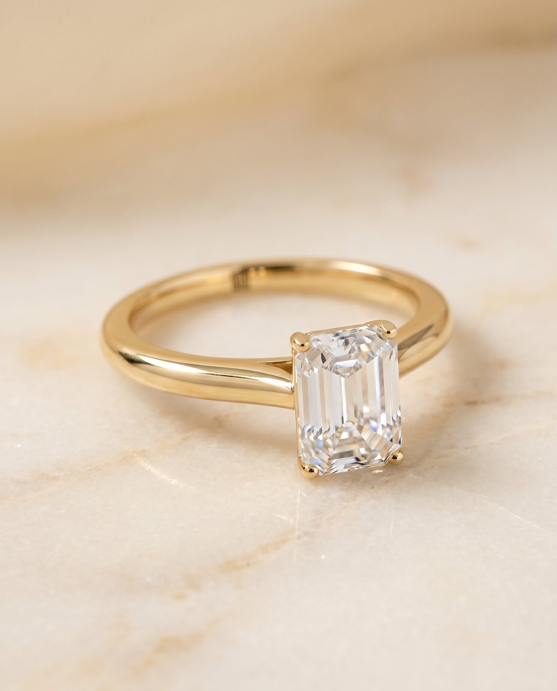 Gladys Select Solitaire Emerald Cut Lab Diamond Engagement Ring in 18K Yellow Gold, shown on hand, angled | RockHer
