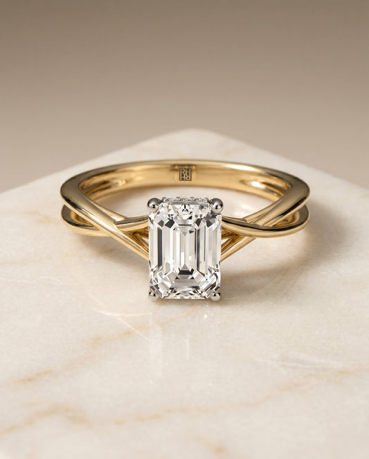 The Grace Twisted Hidden Halo Solitaire Engagement Ring Setting for Emerald Cut Diamonds in 18K Yellow Gold
