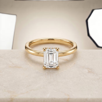 The Lana Secret Halo Adorned Prong Solitaire Emerald Cut Engagement Ring Setting in 18K Yellow Gold