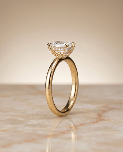 The Lana Secret Halo Adorned Prong Solitaire Emerald Cut Engagement Ring Setting in 18K Yellow Gold