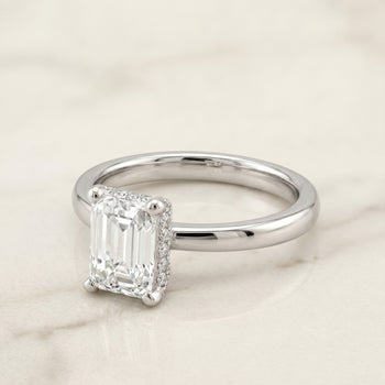 The Lana Secret Halo Adorned Prong Solitaire Emerald Cut Engagement Ring Setting in 18K White Gold