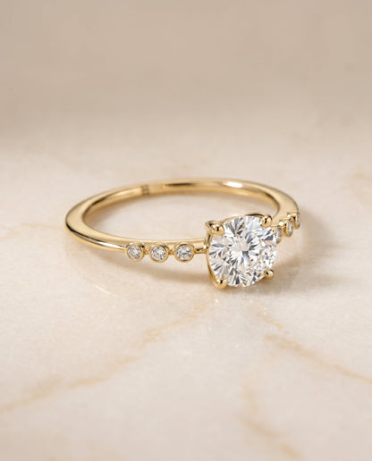 Peggy Select Bezel Accent Solitaire Round Lab Diamond Engagement Ring in 18K Yellow Gold, shown on hand, angled | RockHer