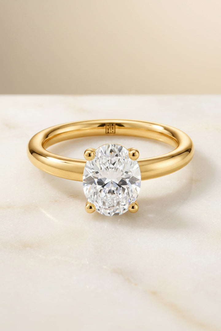 The Tori Select Rounded Comfort Fit Solitaire Oval Lab Diamond Engagement Ring in 18K Yellow Gold, shown on hand, angled | RockHer