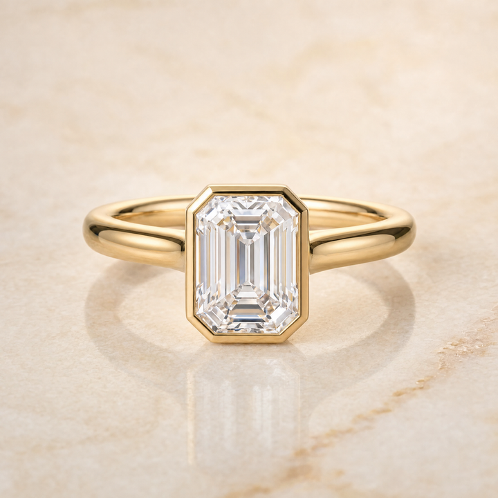 The Duran Simple Bezel Solitaire Emerald Cut Engagement Ring Setting in 18K Yellow Gold